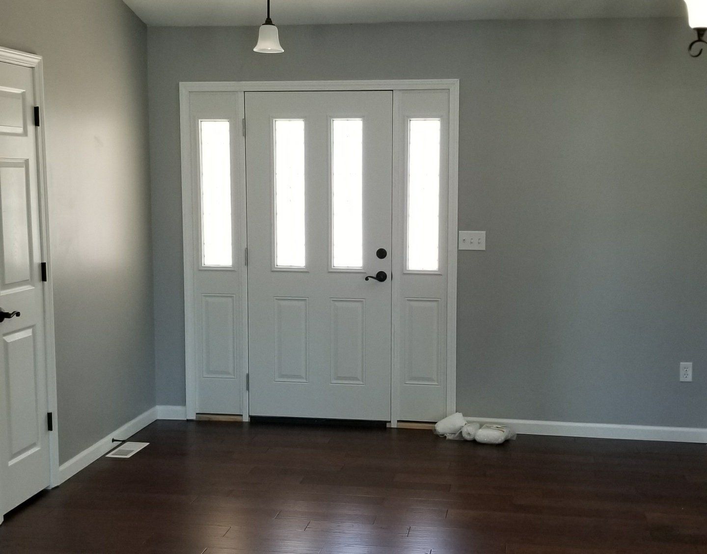 An empty room with a white door and a light hanging from the ceiling.
