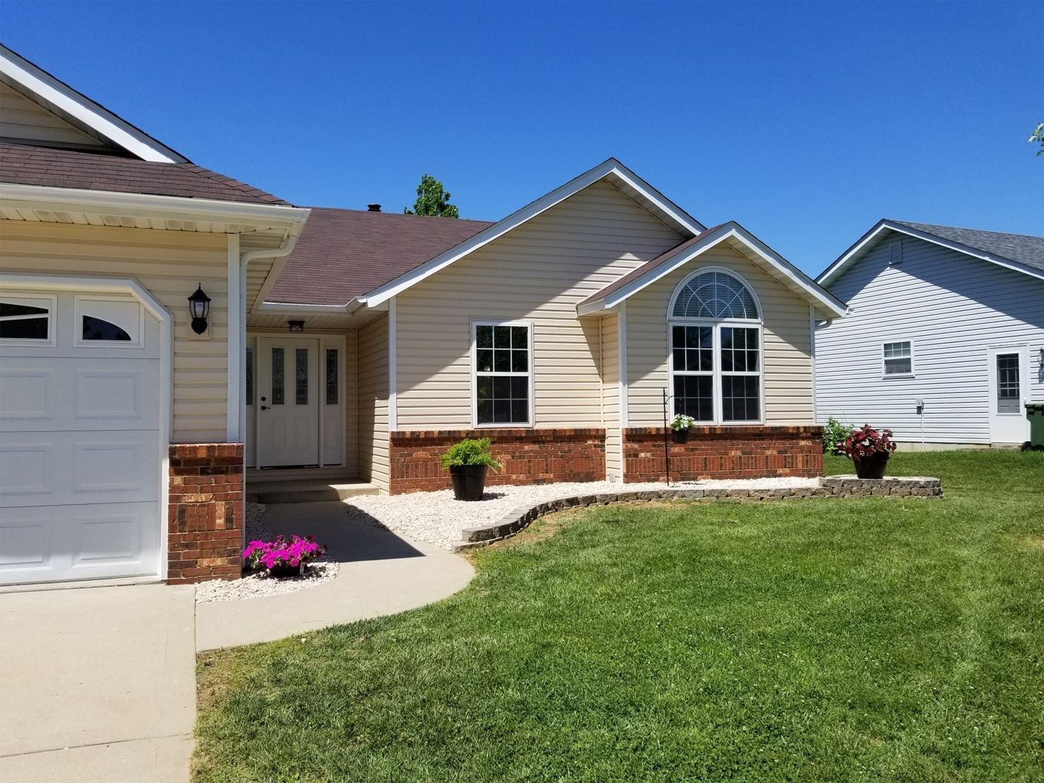 A house with a white garage door and a large lawn in front of it.