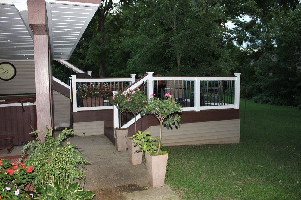 A deck with a white railing and potted plants