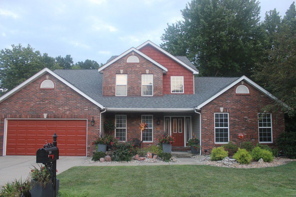 A large red brick house with a mailbox in front of it