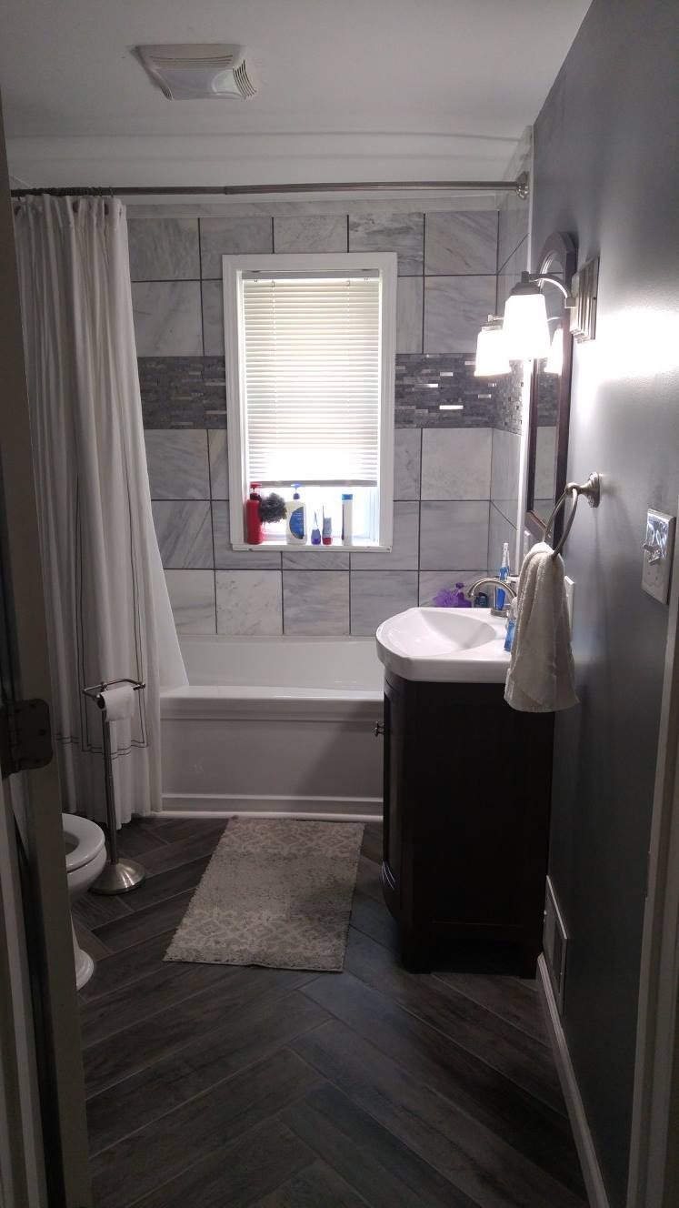 A bathroom with a sink , tub , toilet and window.