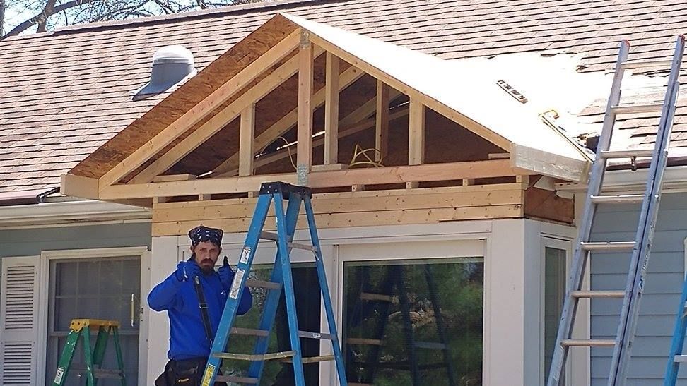 A man standing on a ladder in front of a house under construction