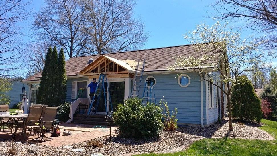 A blue house with a porch being built on top of it.
