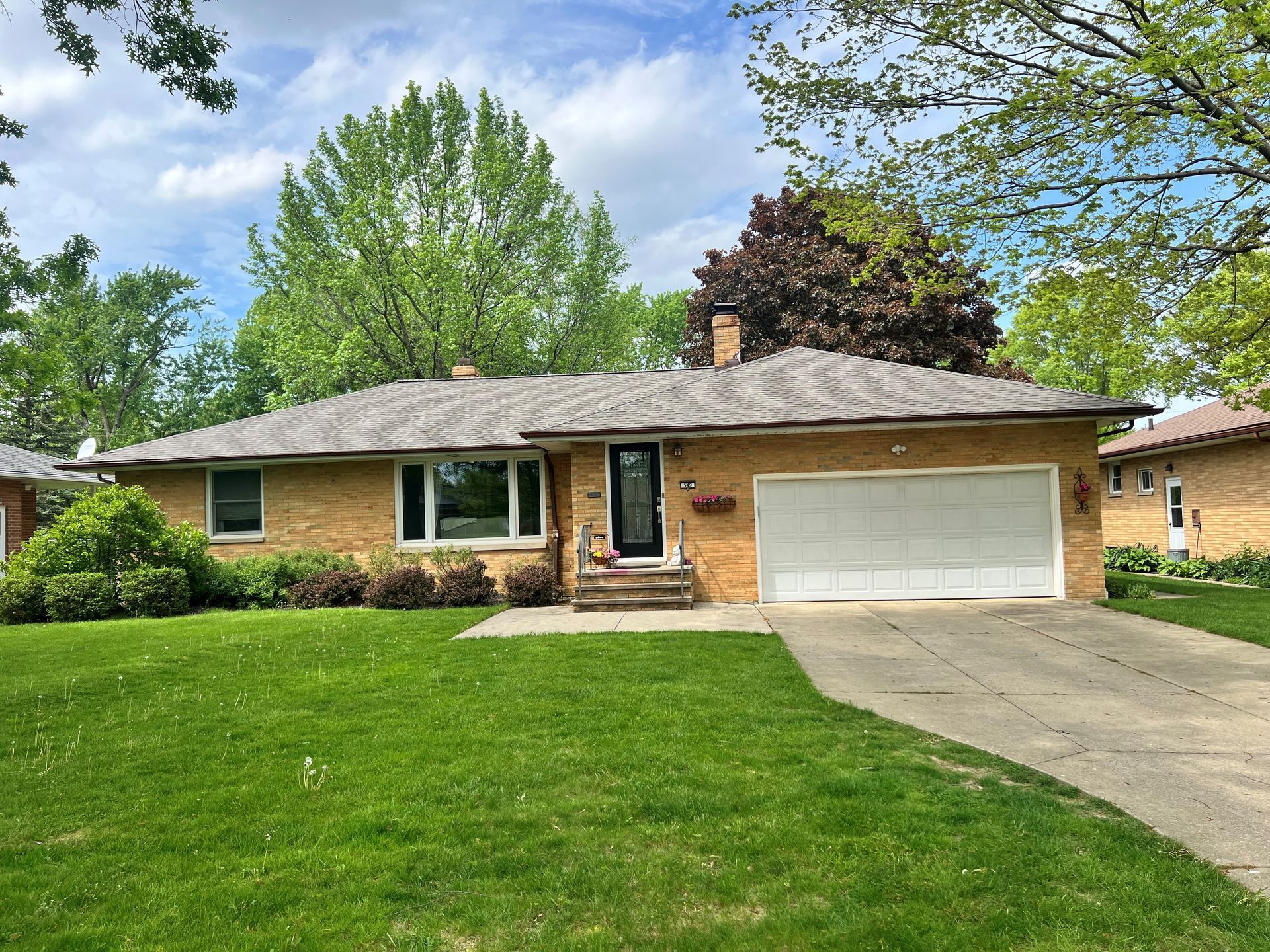 A brick house with a white garage door and a lush green lawn.