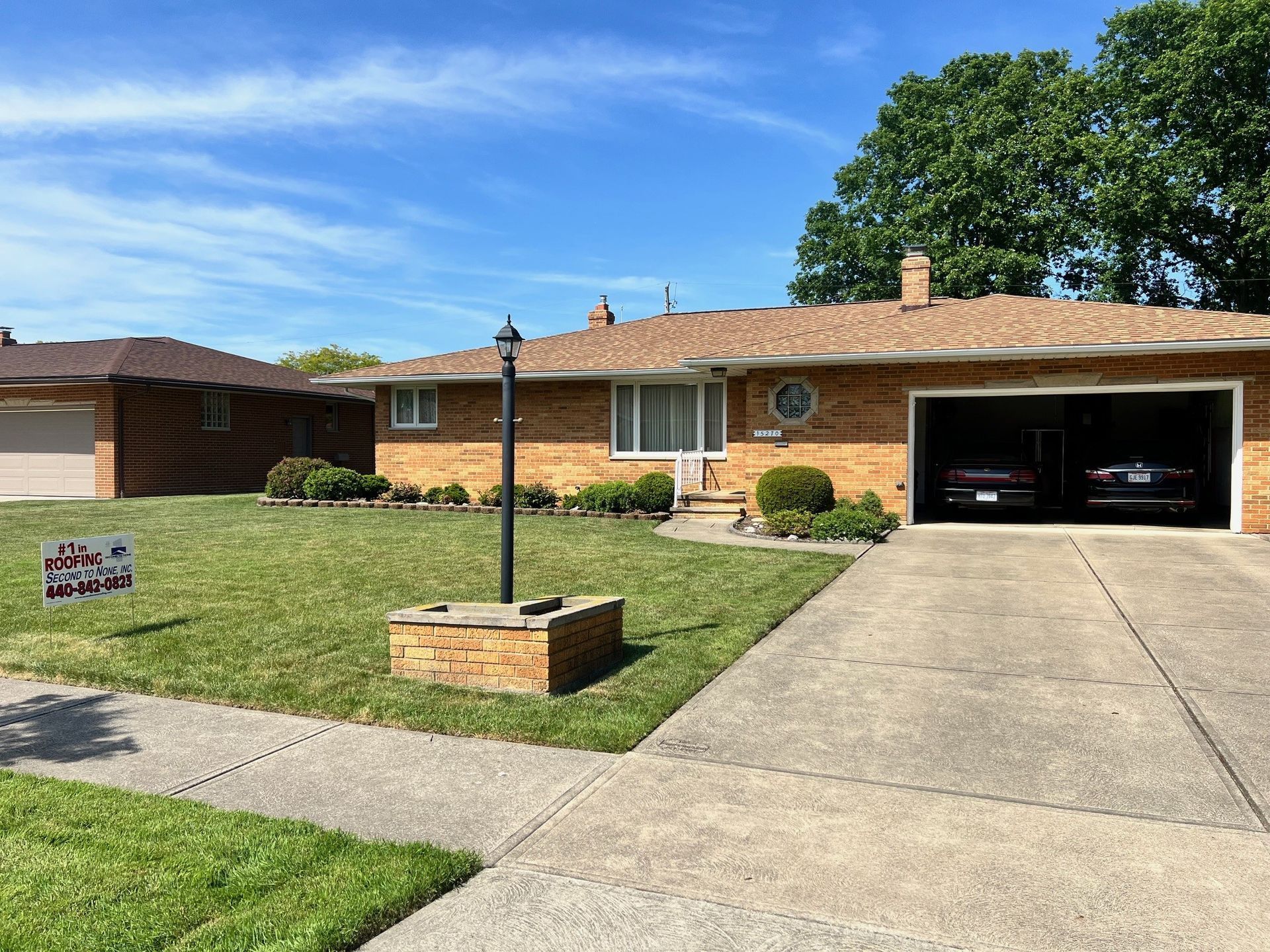 A brick house with a garage and two cars parked in it