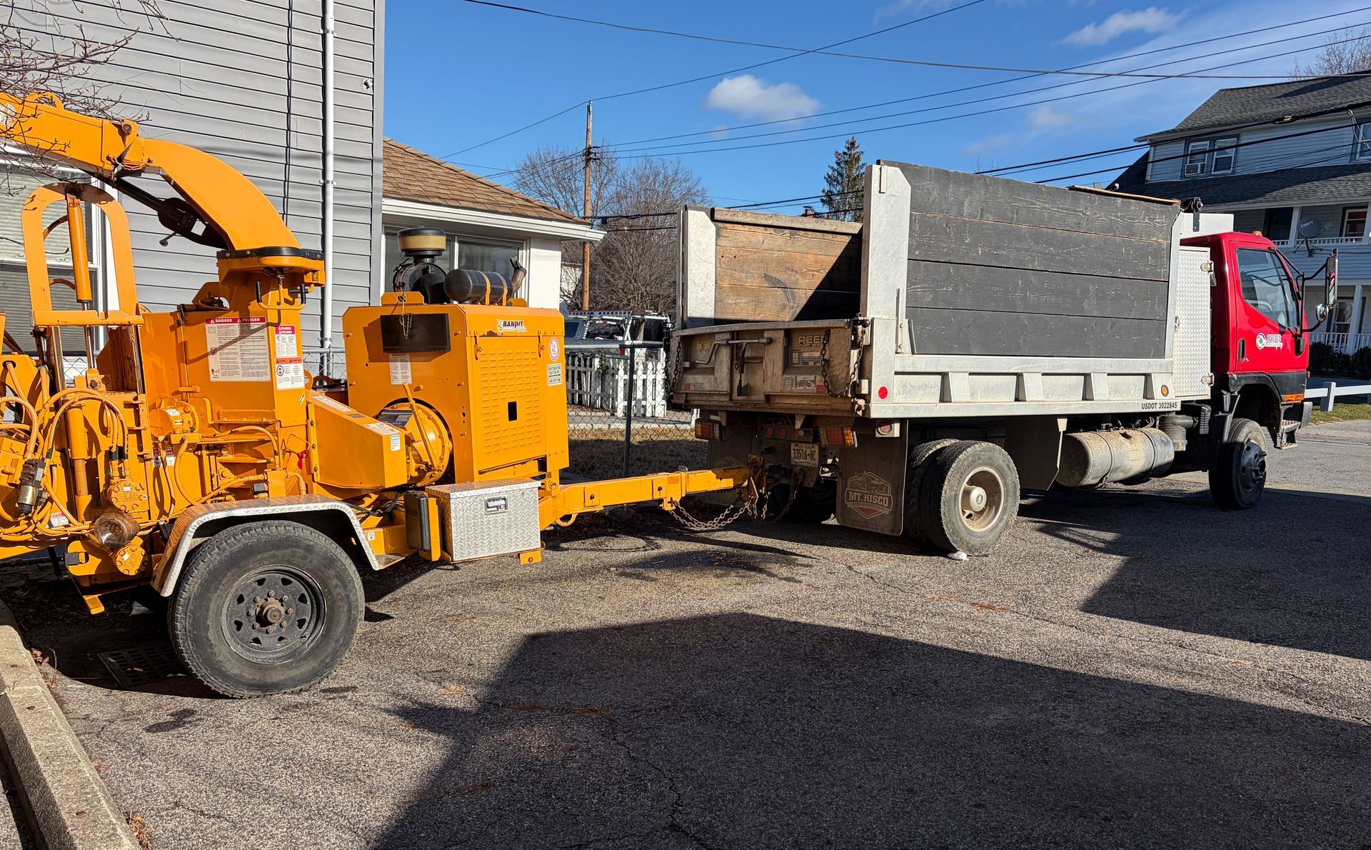 Orange wood chipper and truck parked outside.