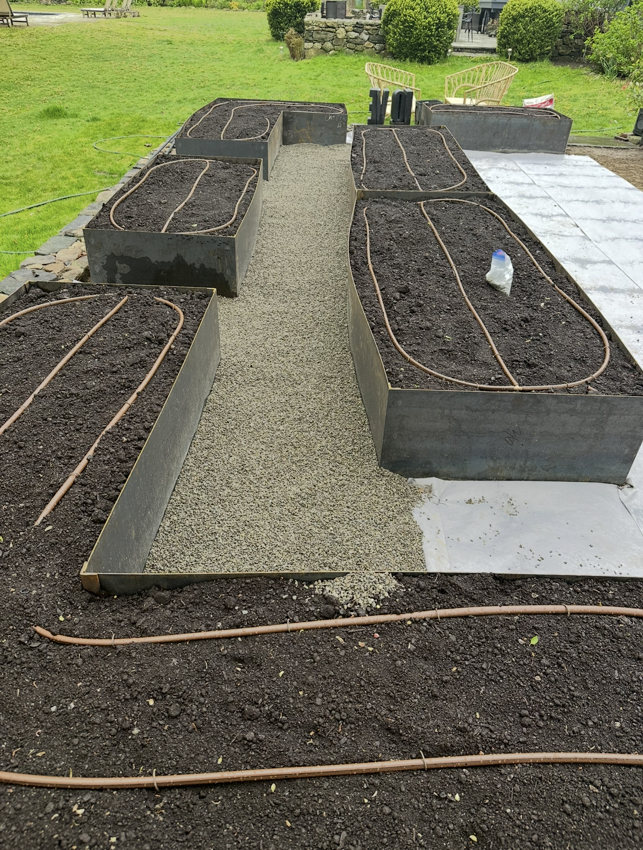 Raised garden beds filled with soil, gravel path, and irrigation lines.