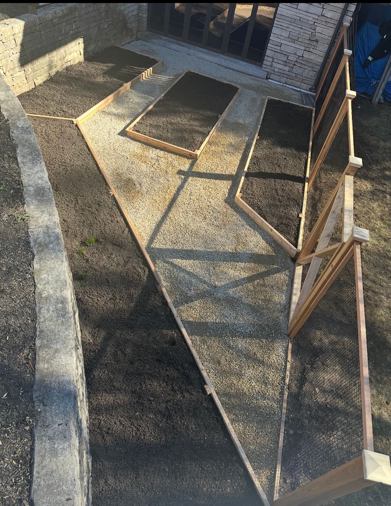 Construction site with angled concrete walkways, brick wall, and wood supports.