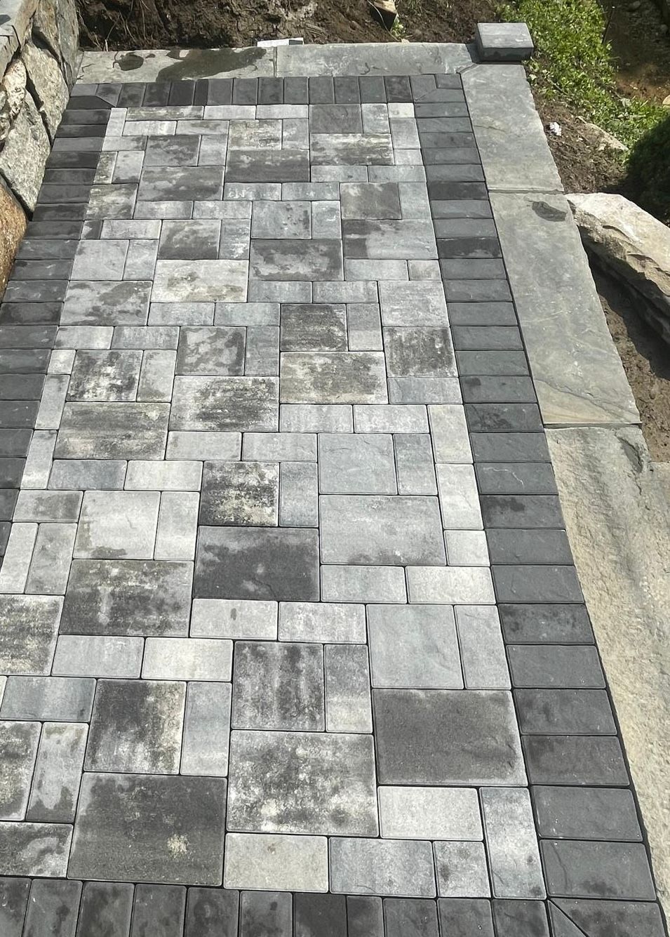 Stone paver walkway with dark gray border and central pattern.