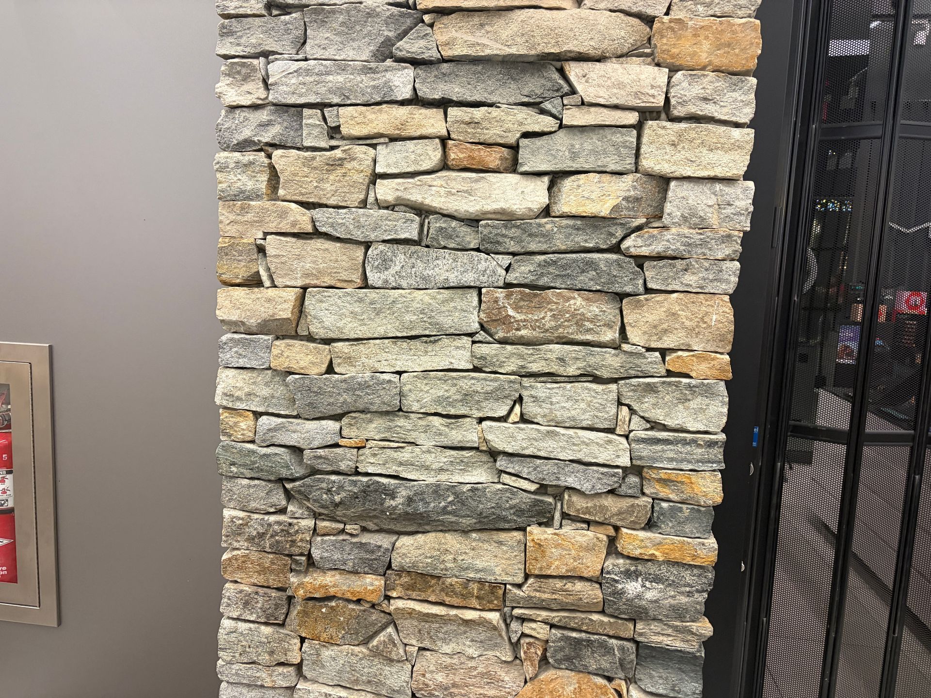 Stone pillar with varied colors, next to a metal security gate.
