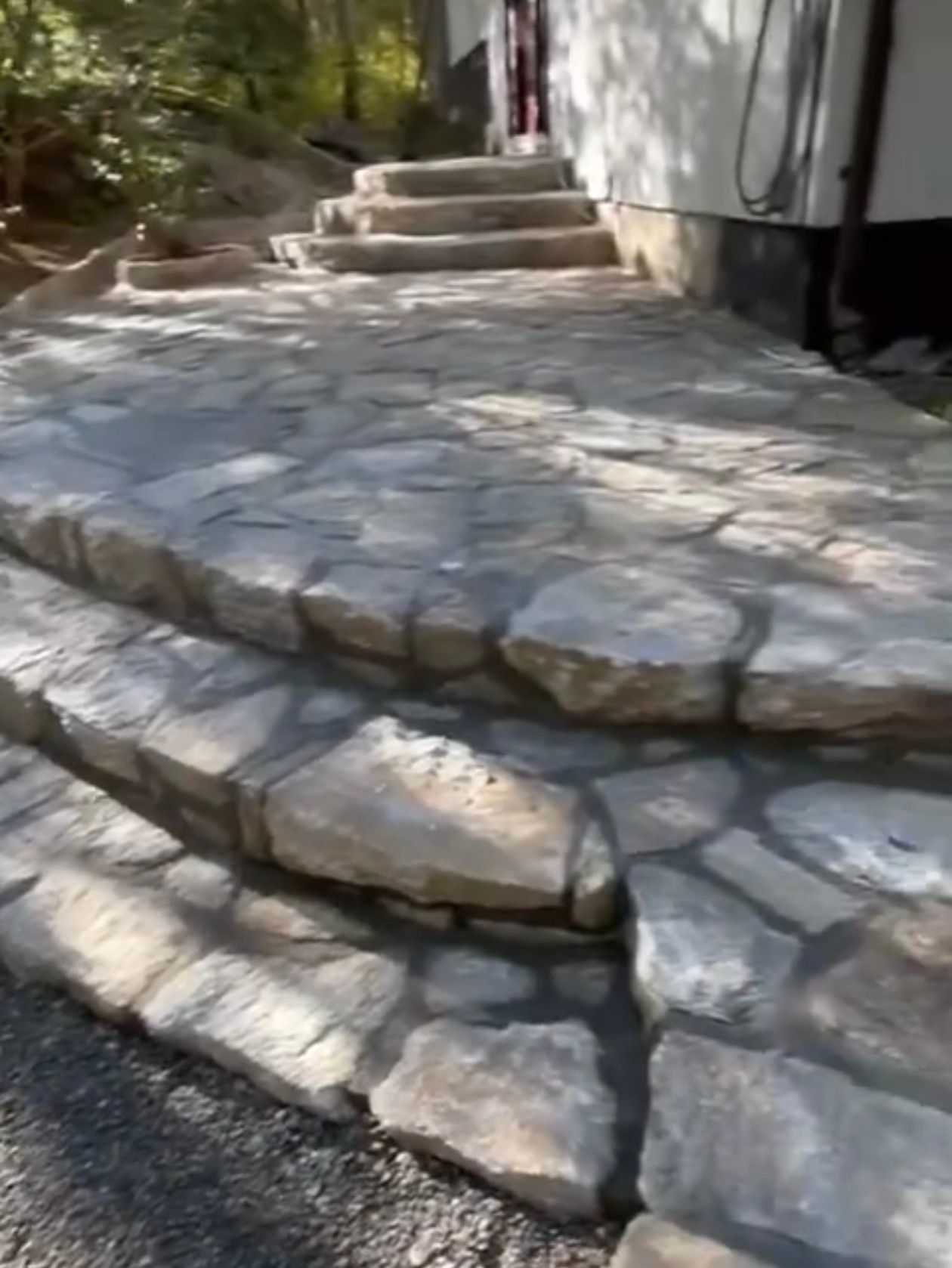 Stone steps and walkway leading to a building's entrance. Gray stone construction in an outdoor setting.