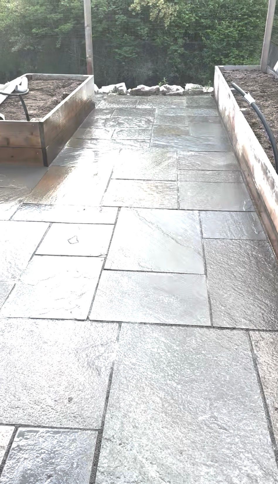 Wet stone patio with raised garden beds on either side.