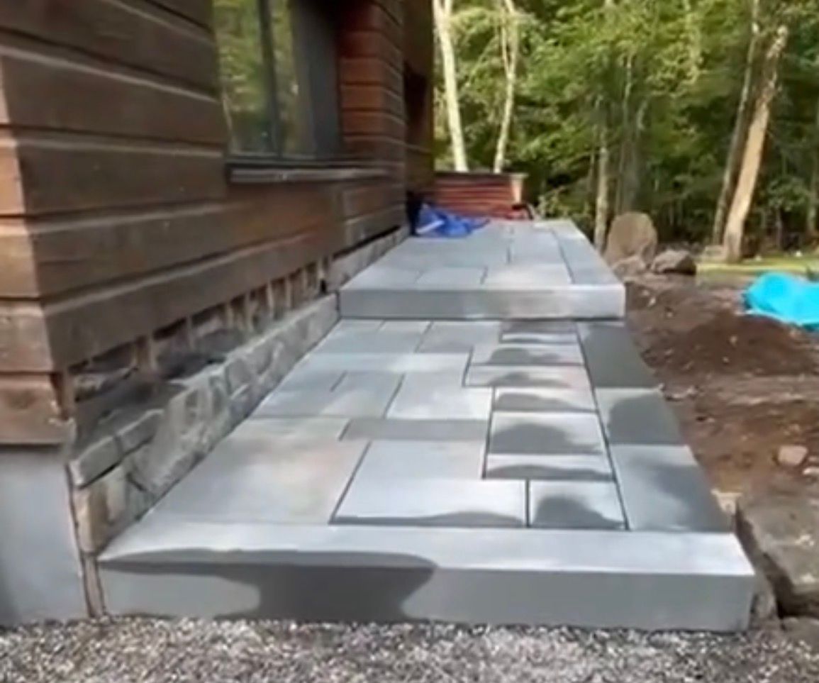 Stone steps leading up to a wooden building, set in a natural outdoor environment.