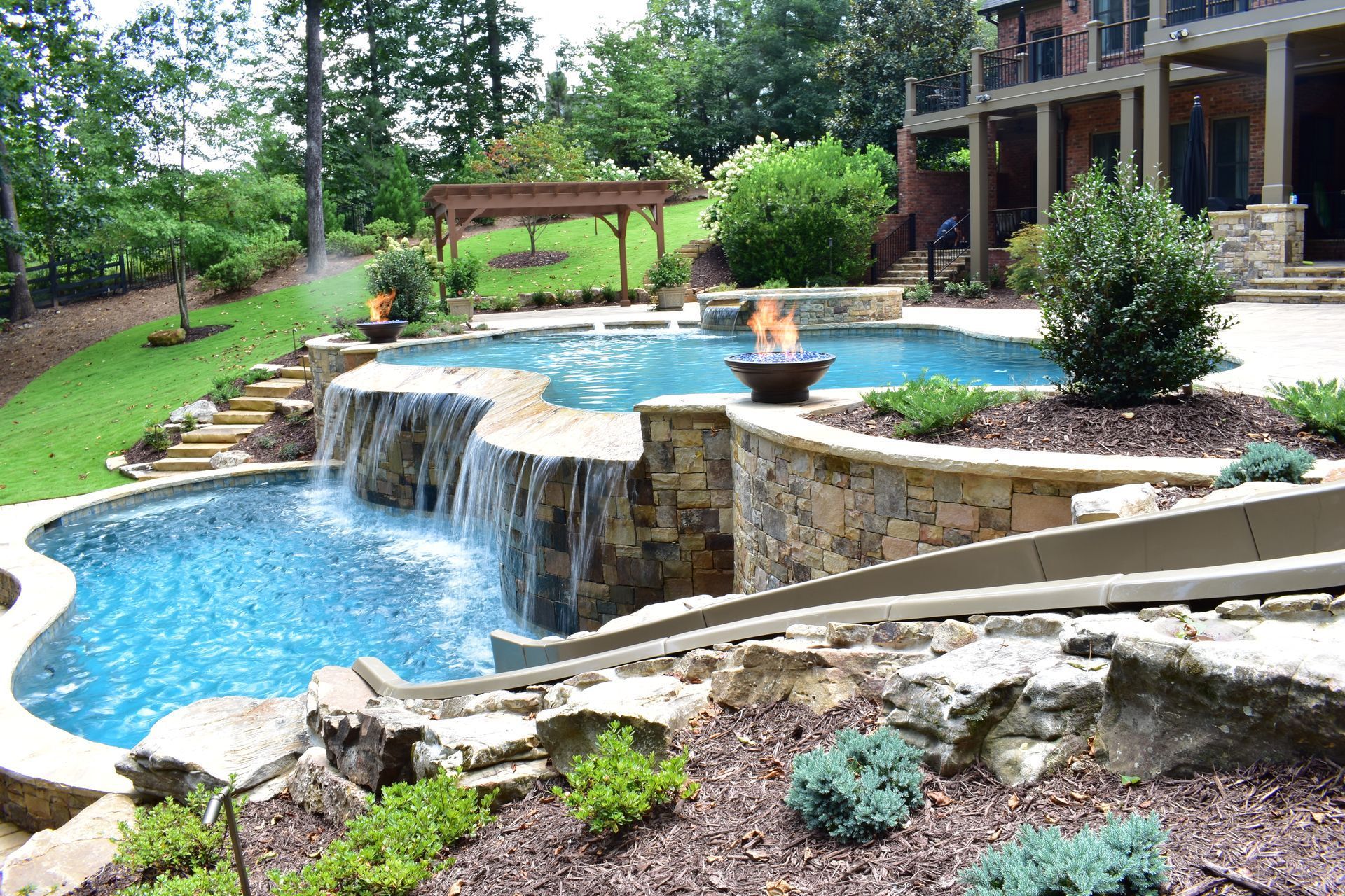 A fire pit is sitting on a brick patio in front of a house.