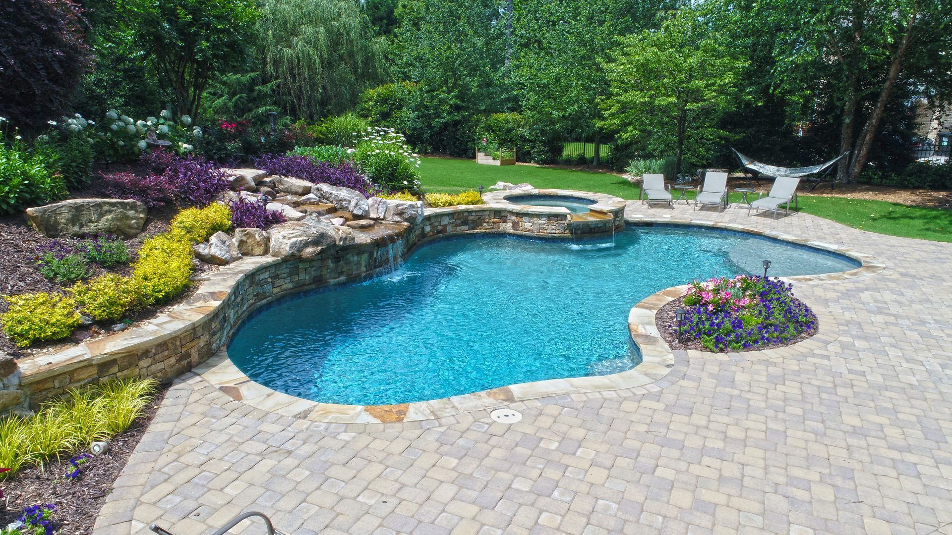 A waterfall in a swimming pool with a fence in the background