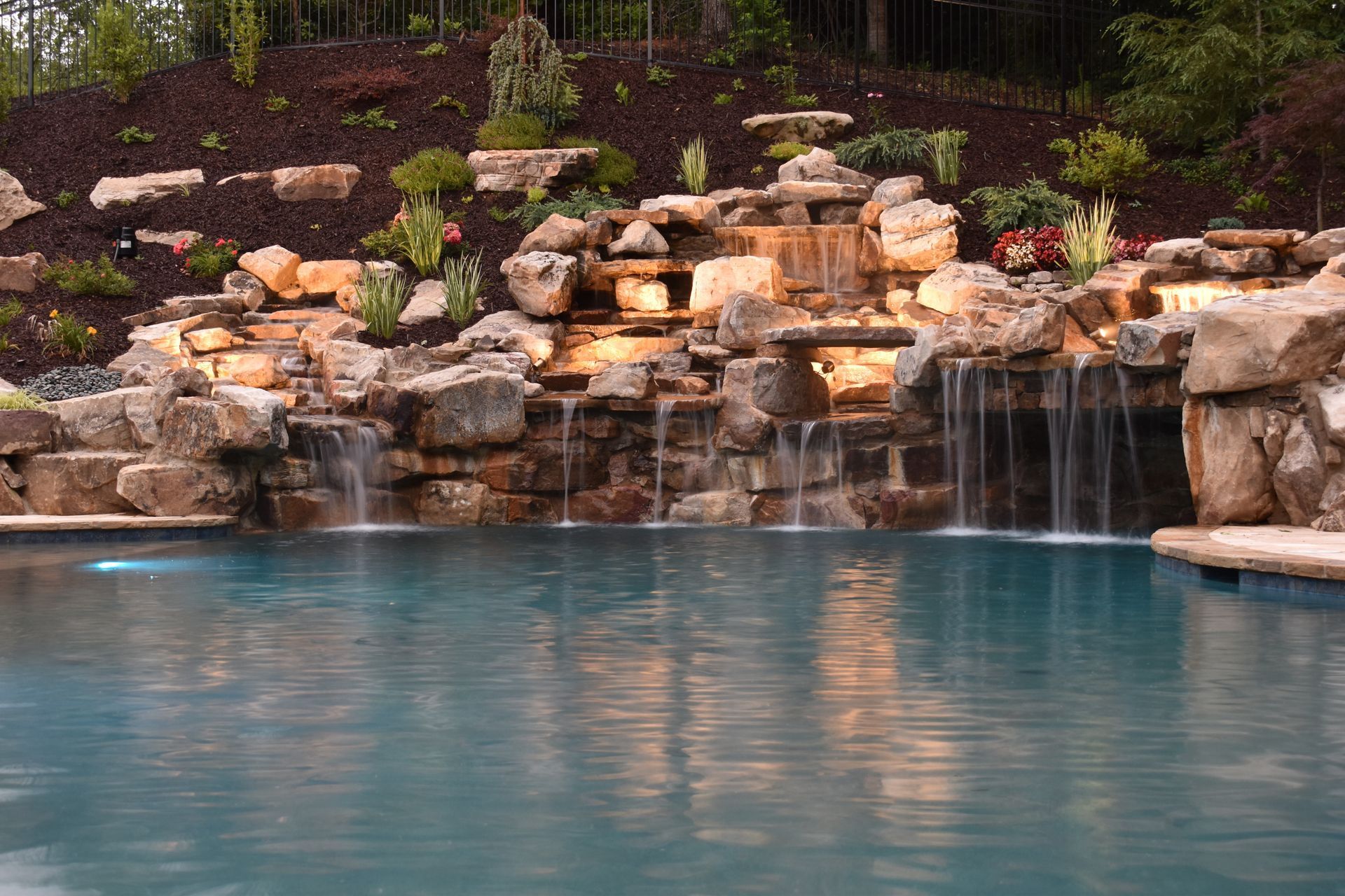 A large swimming pool with a waterfall in the middle of it.