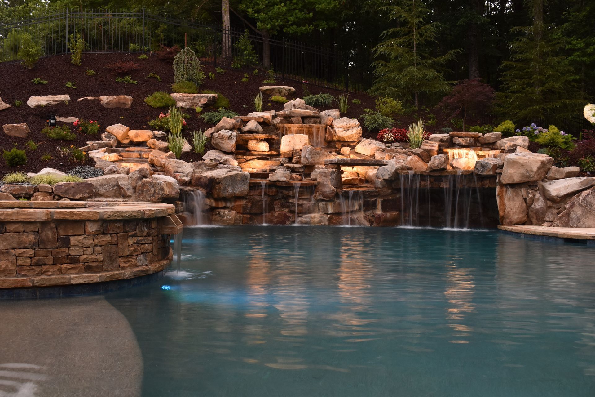 A large swimming pool is lit up at night with purple lights.