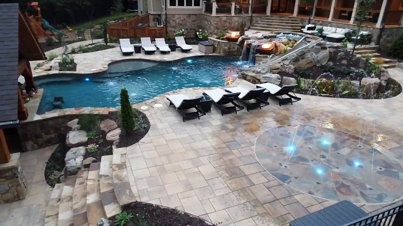 A waterfall is surrounded by rocks next to a swimming pool.