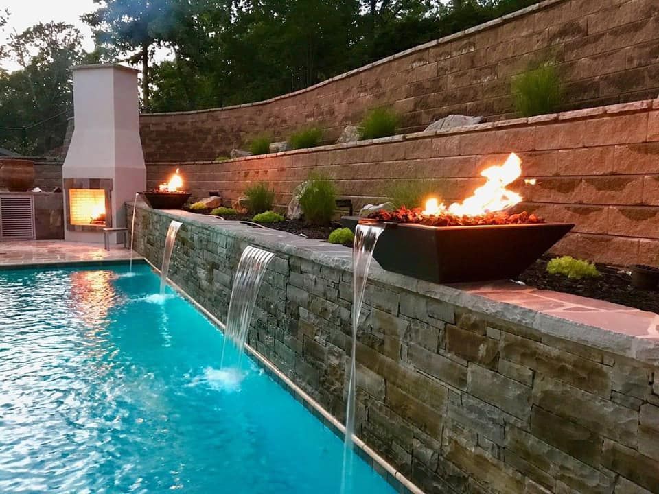 A swimming pool with a waterfall and a fire pit