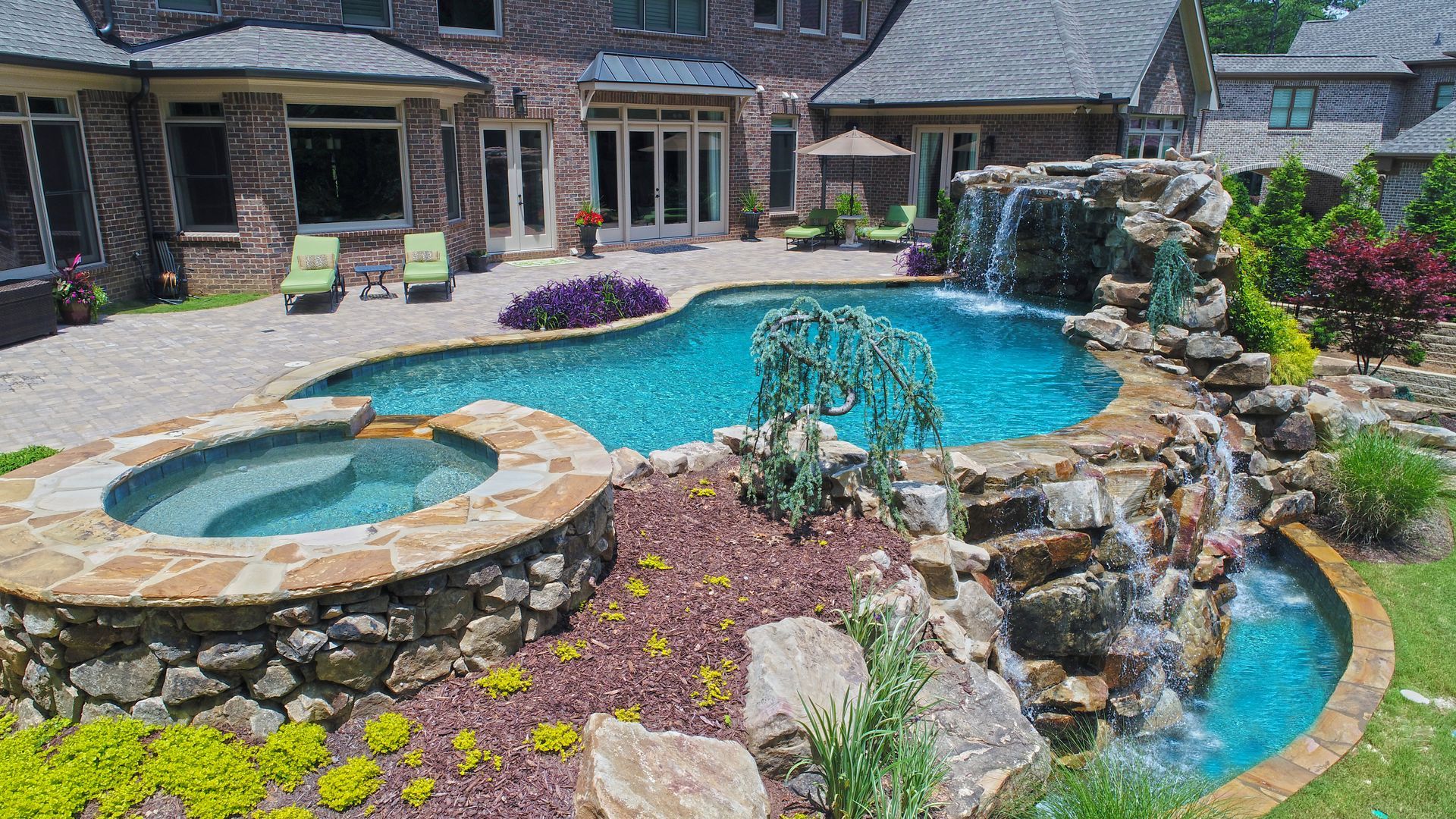 A large swimming pool with a waterfall in the backyard of a house