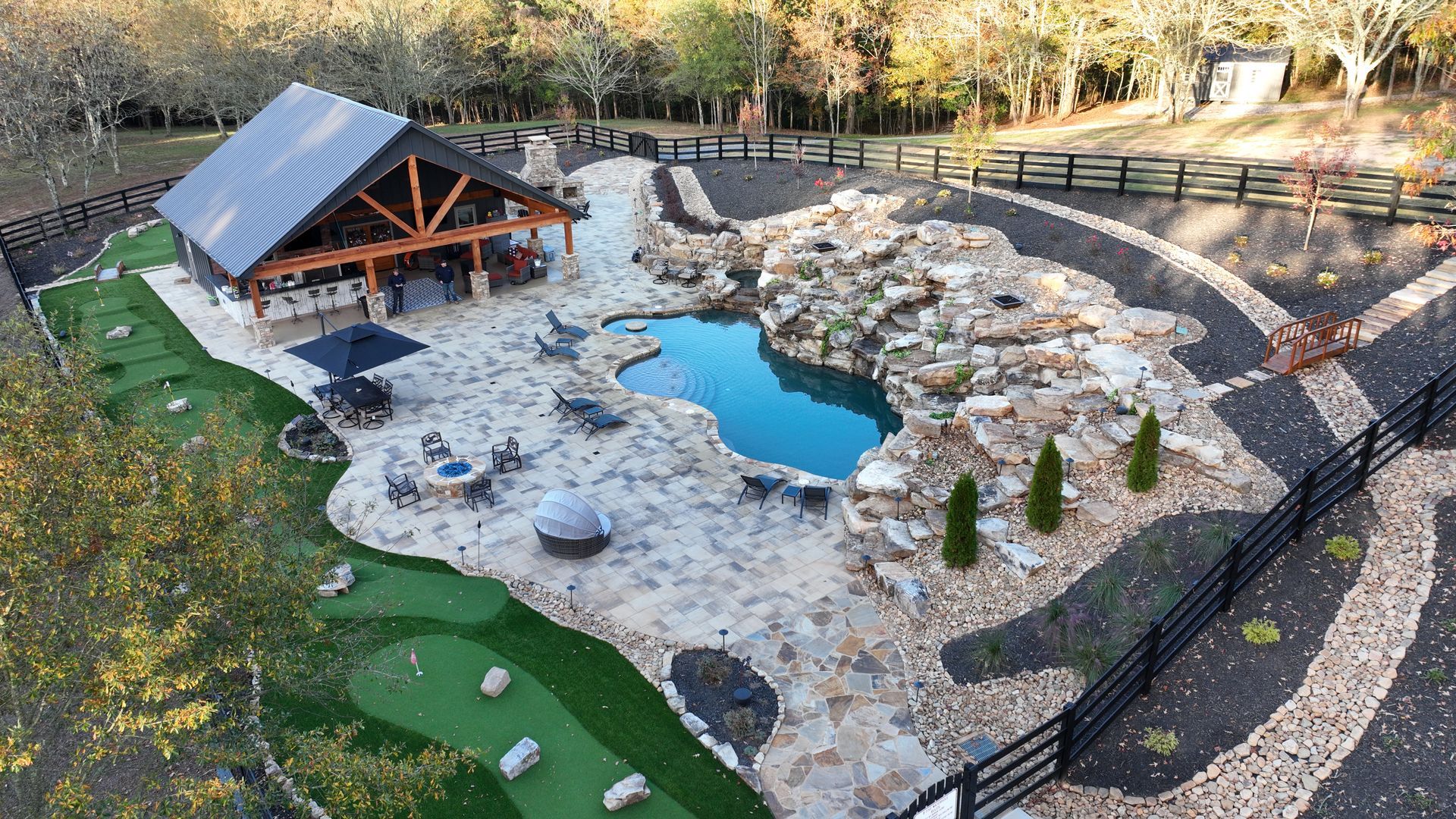 An aerial view of a large backyard with a pool and a putting green
