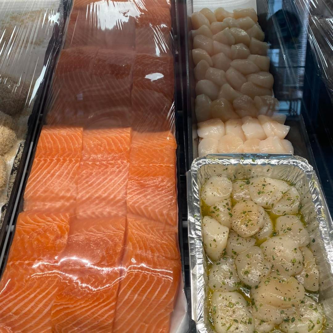 Fresh seafood display: salmon fillets, scallops, and prepared scallops.