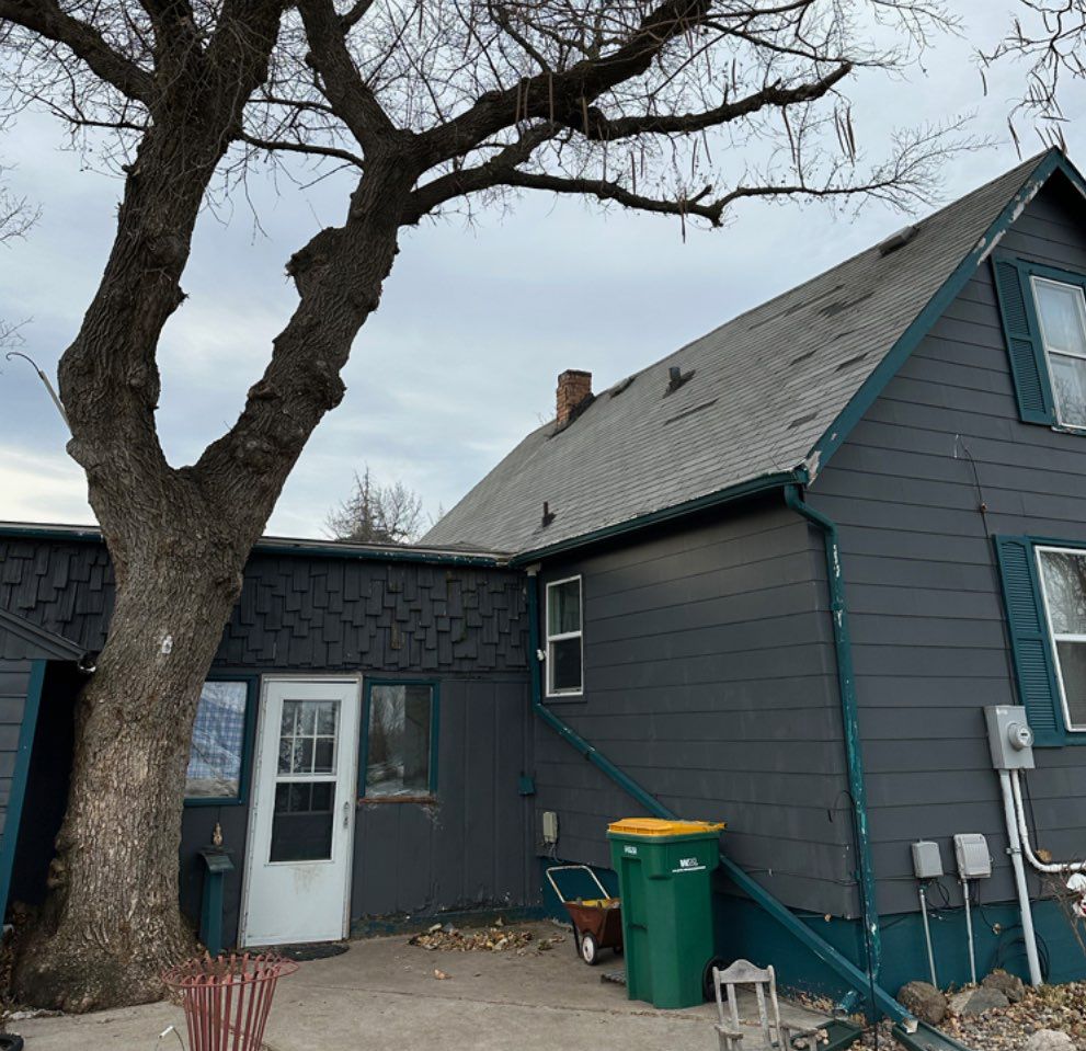 A gray house with a tree in front of it