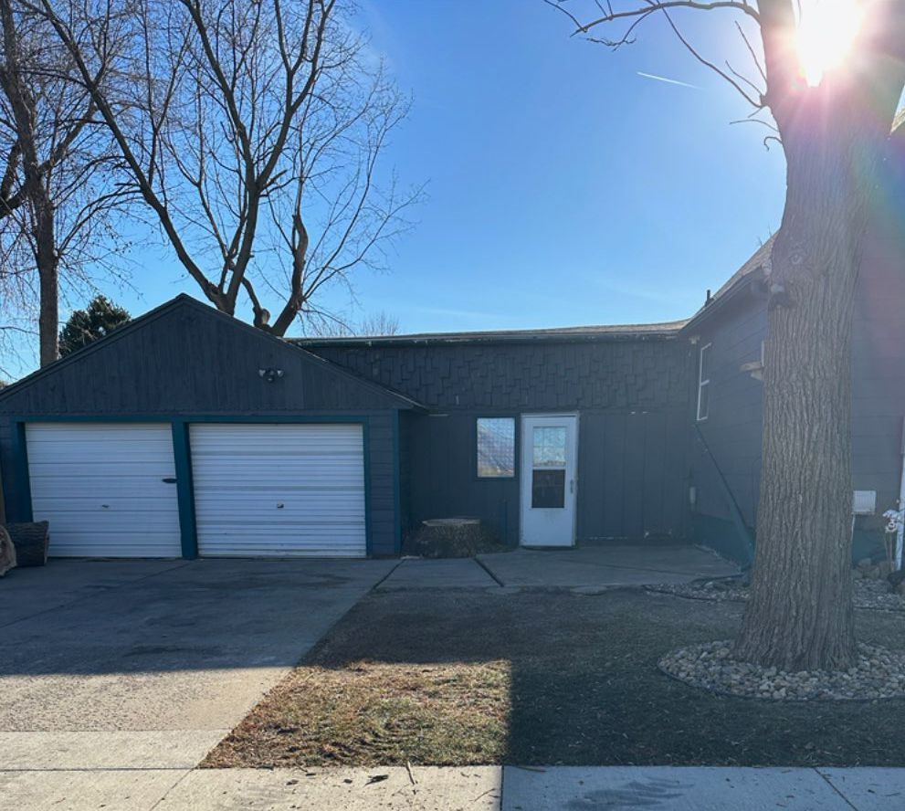 A house with two garage doors and a tree in front of it