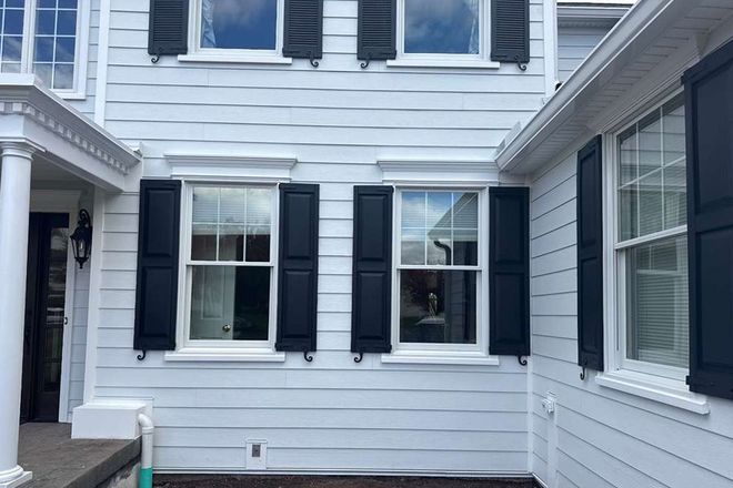 White house siding with black shutters and windows in a narrow courtyard between two buildings