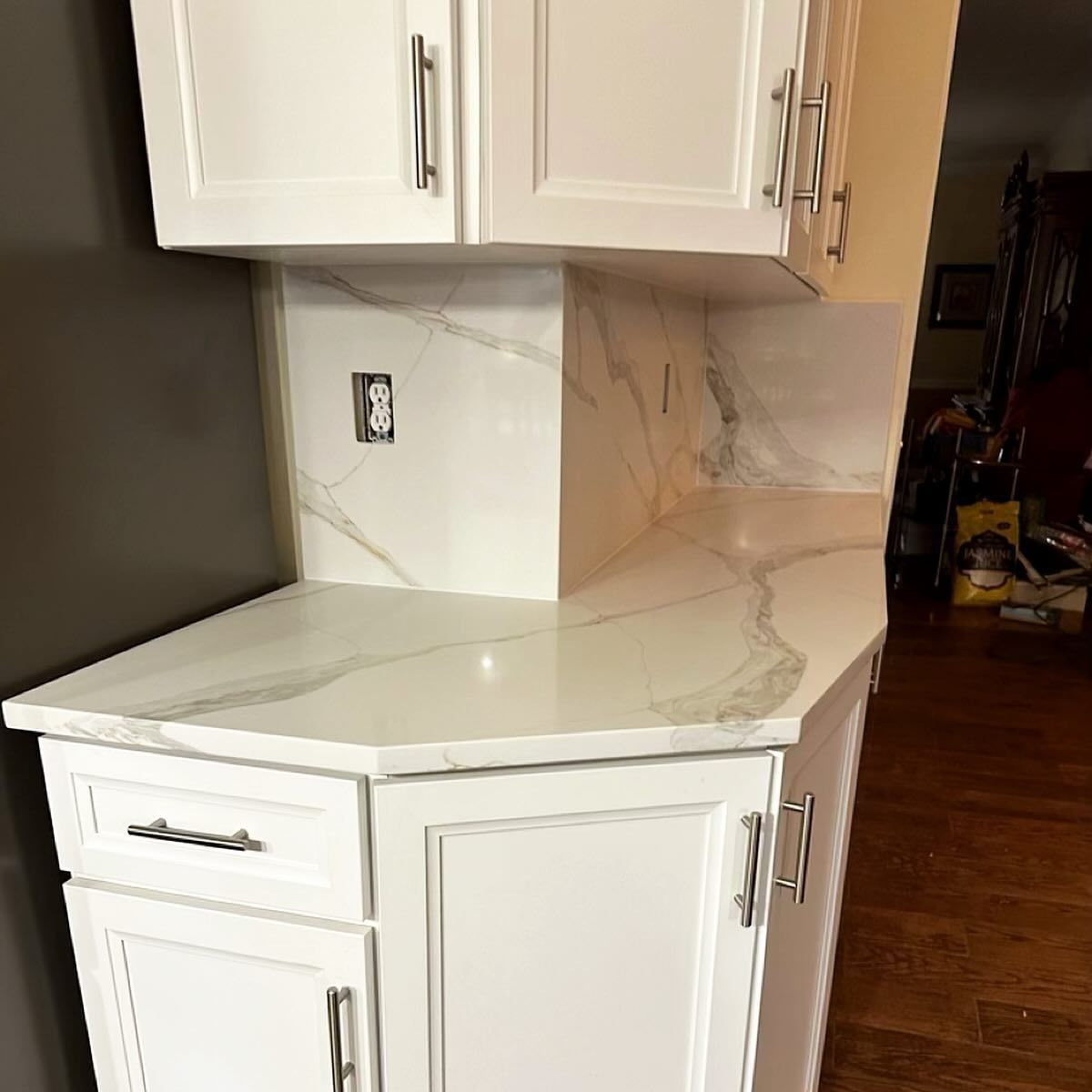 White kitchen cabinets with marble-patterned countertops and backsplash.