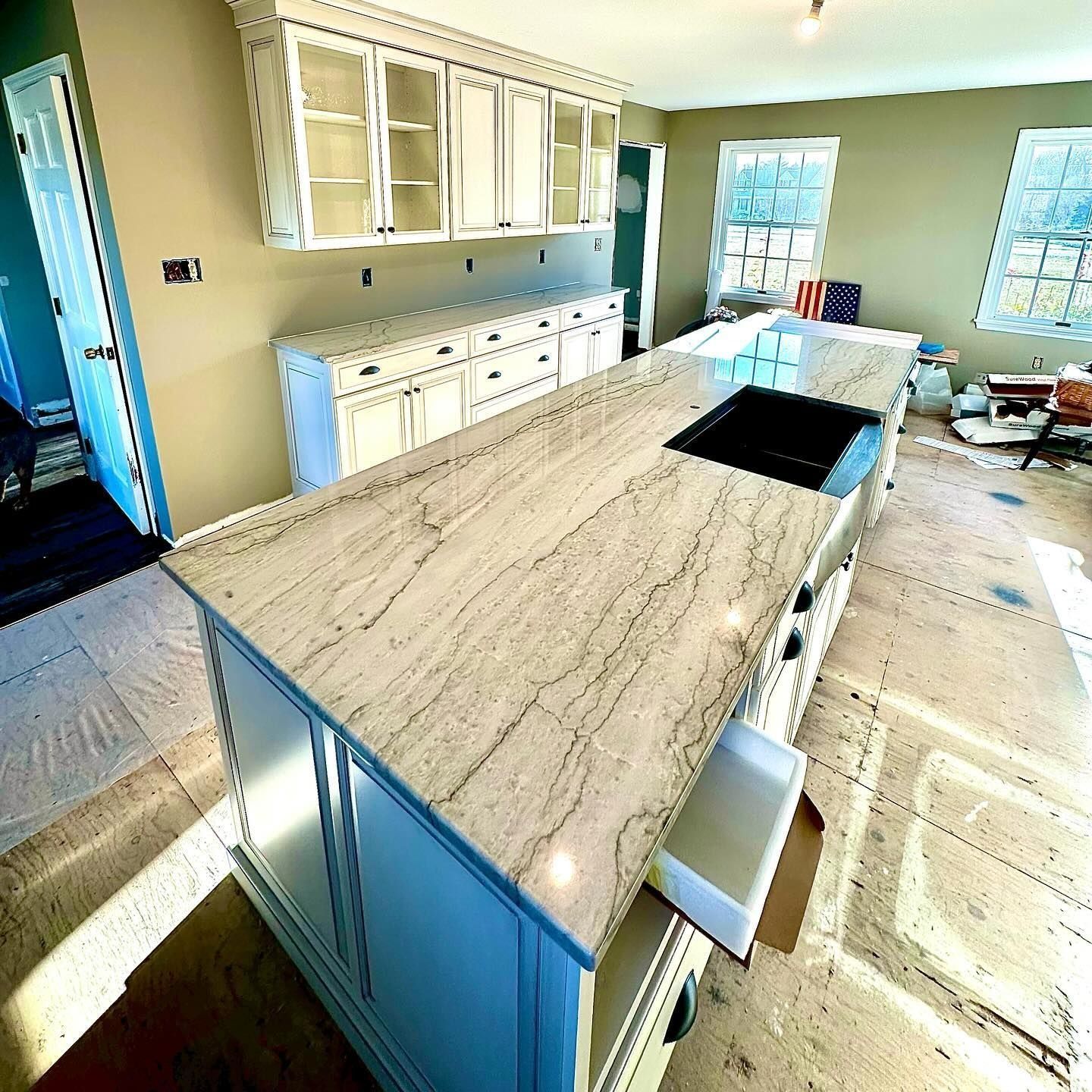 White kitchen with island, light countertops, upper cabinets, and a cooktop.
