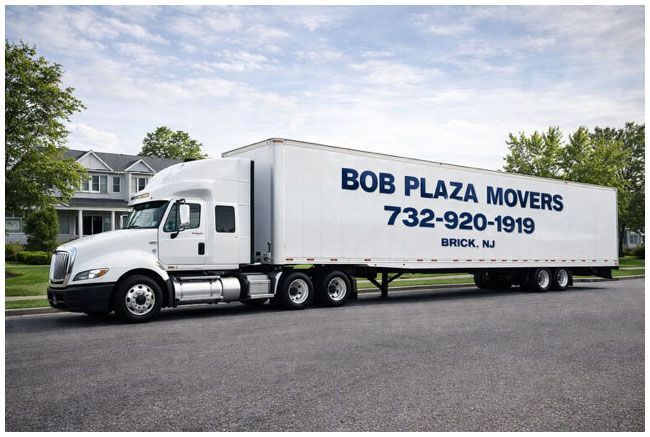 White Bob Plaza Movers truck parked on a street in front of a house.