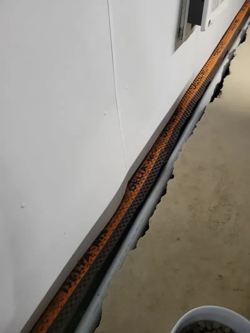 Orange cable run along wall in a narrow hallway beside a gray floor strip