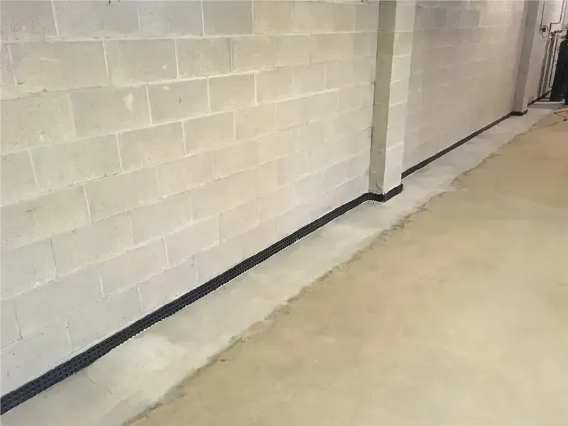 Empty concrete hallway with cinderblock wall and a dark floor edge strip
