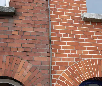 Close-up of a brick building facade with two windows and a vertical seam down the center.