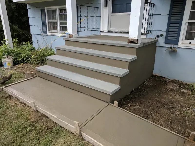 Concrete front porch with five steps and a sloped wheelchair ramp leading to a house entrance