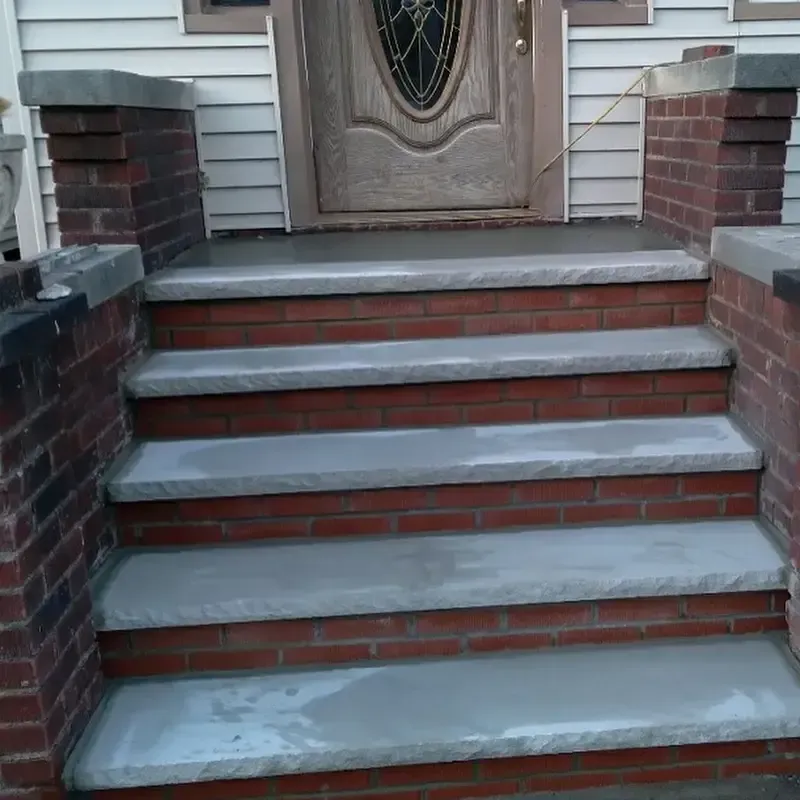 Brick front steps leading to a front door with concrete treads and brick side walls