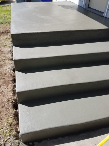 Freshly poured concrete steps leading to a raised slab outdoors