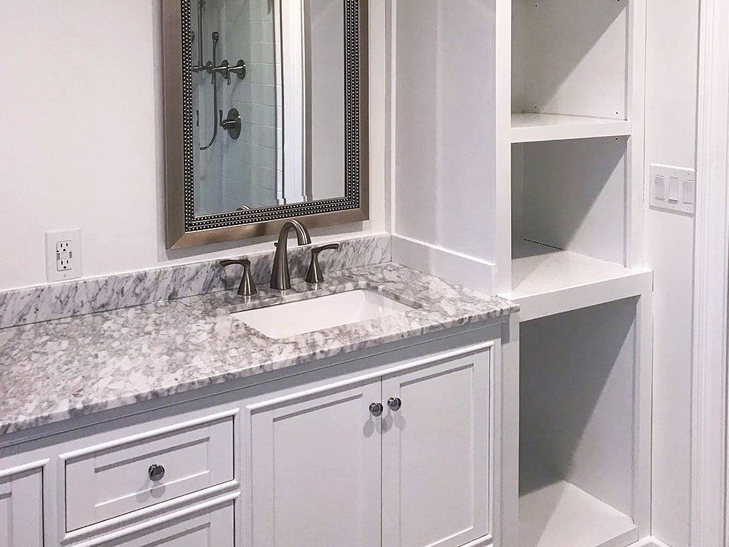 A bathroom with a sink , mirror and shelves.