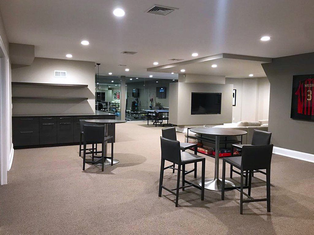 A basement with tables and chairs and a television.