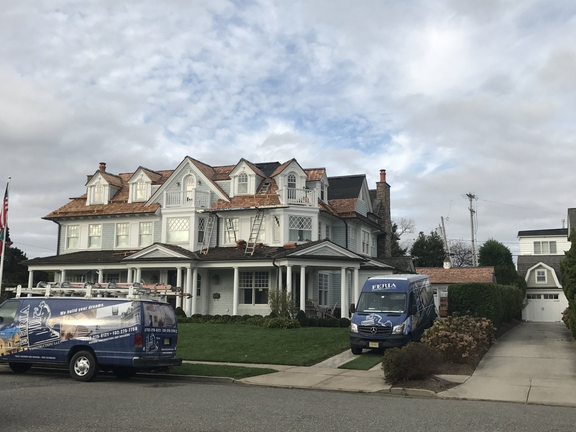 Two vans are parked in front of a large house