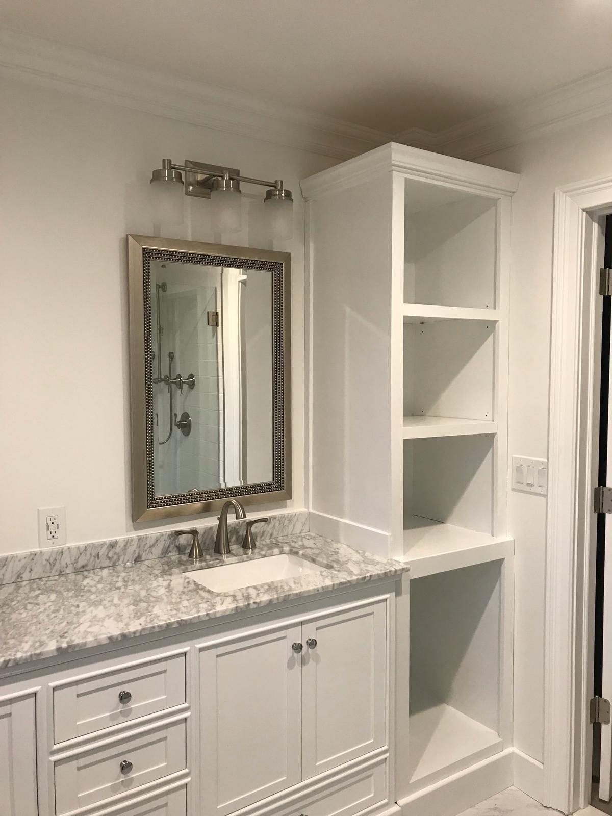 A bathroom with a sink , mirror and shelves.