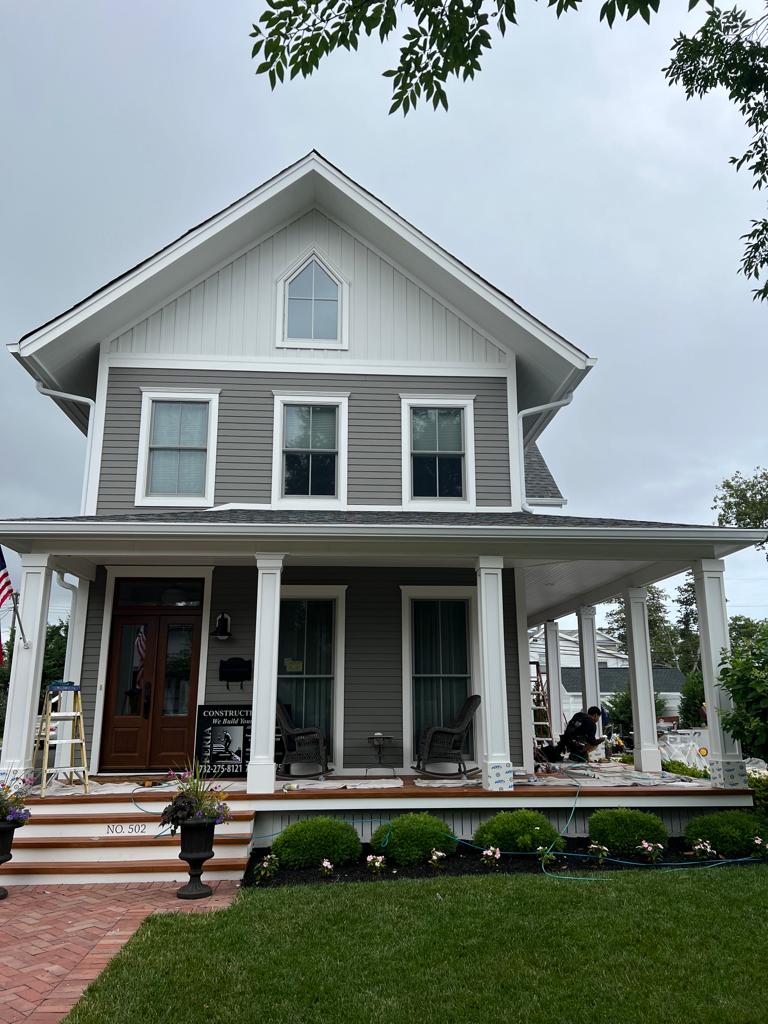 A large gray and white house with a large porch.