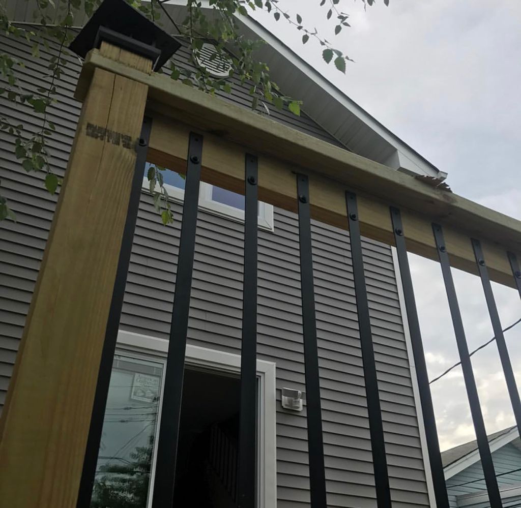 A house with a black railing and a wooden post