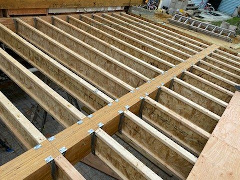 A wooden floor under construction with a ladder in the background.