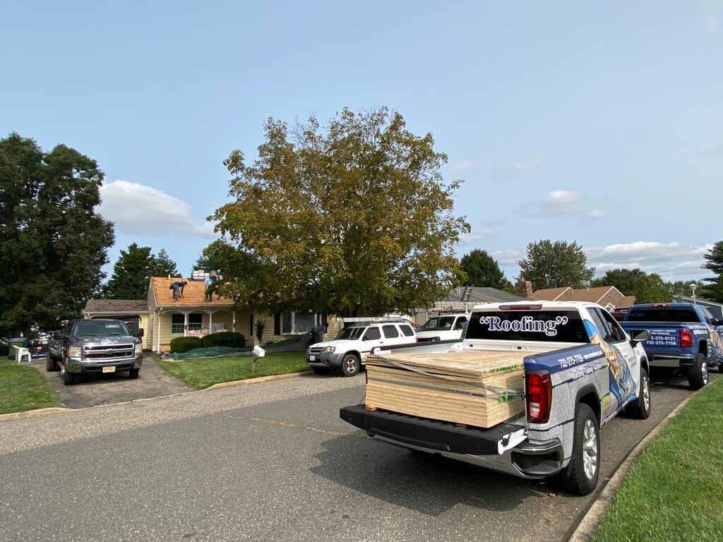 A truck is driving down a street with a stack of wood in the back.