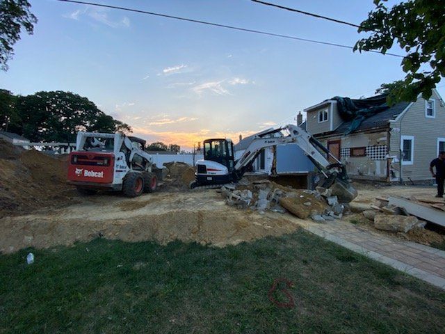 A couple of tractors are parked in front of a house.
