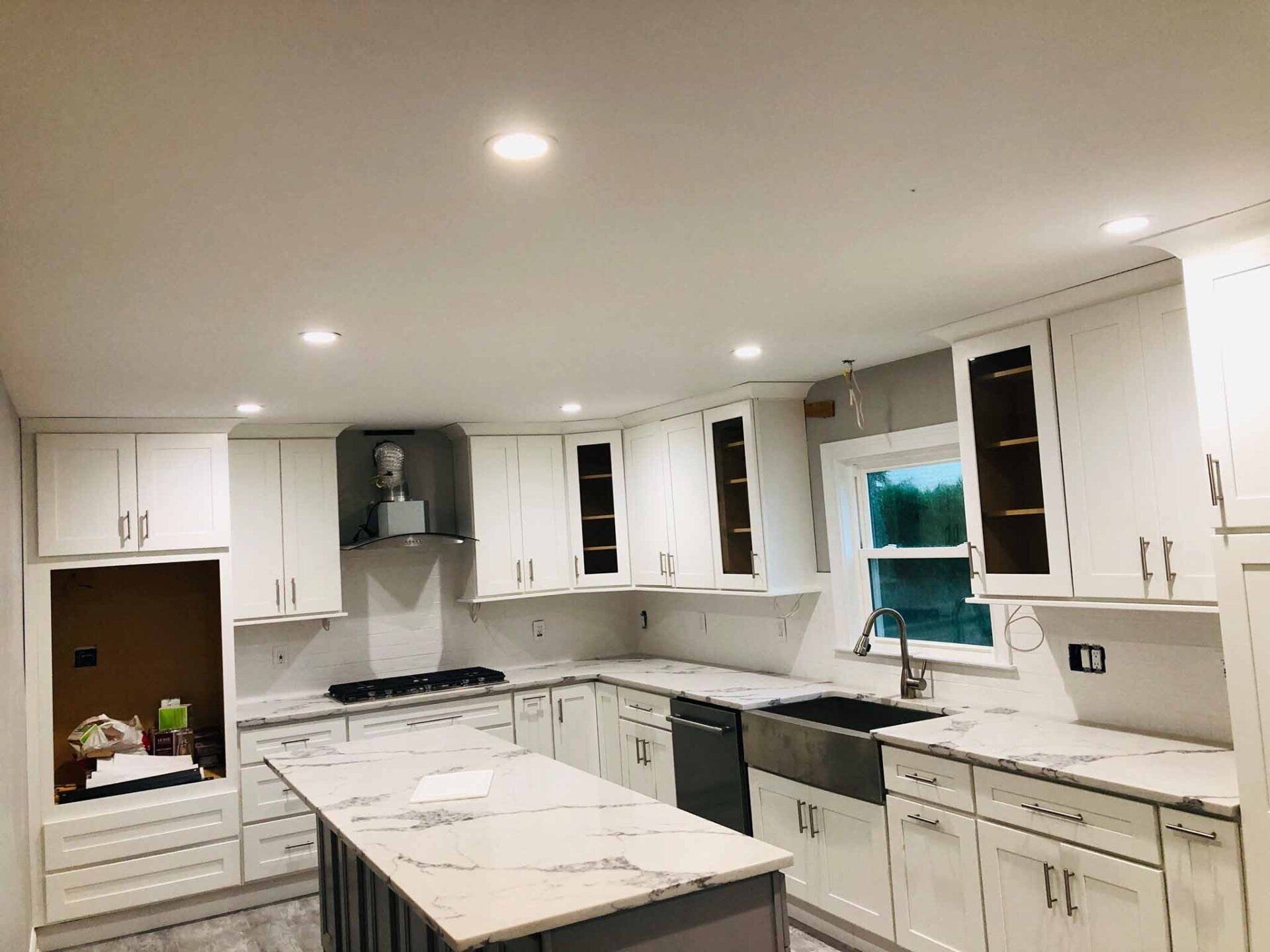 A kitchen with white cabinets , granite counter tops , a sink , and a large island.