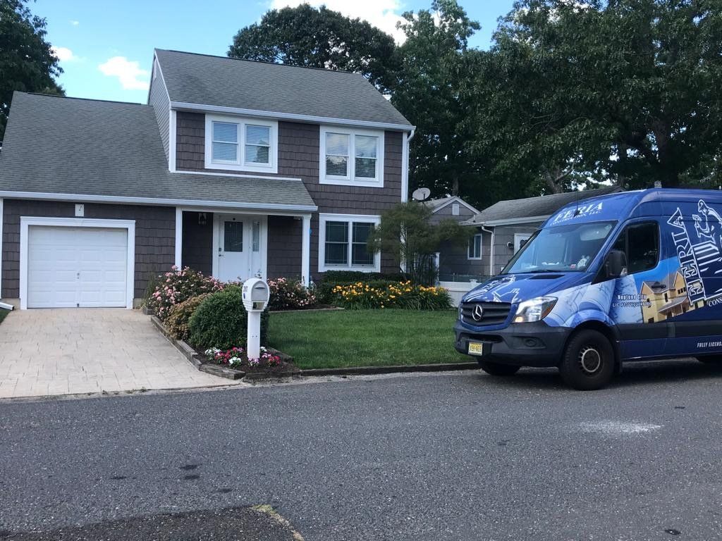 A blue van is parked in front of a house