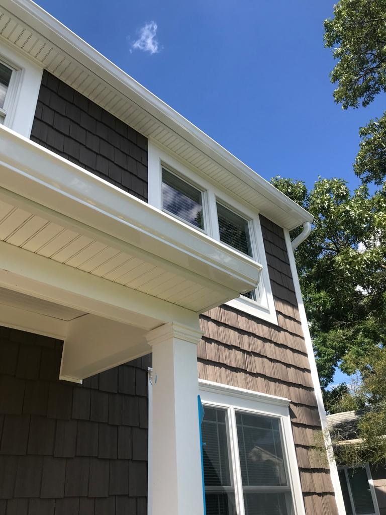 A house with a white gutter and a blue sky in the background.